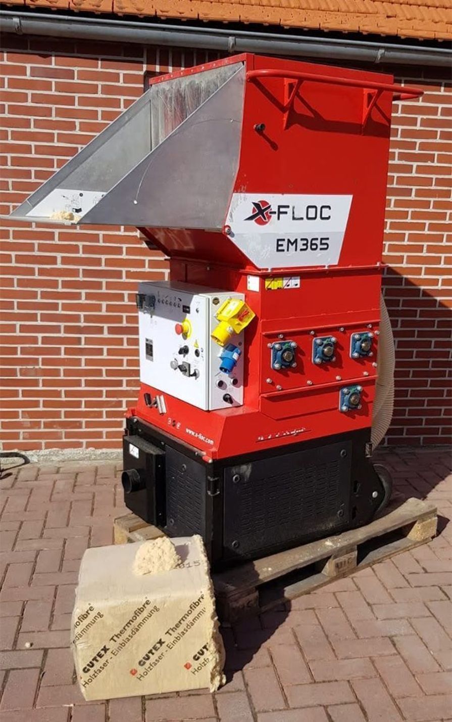 Rote Einblasmaschine steht vor einer roten Backsteinwand